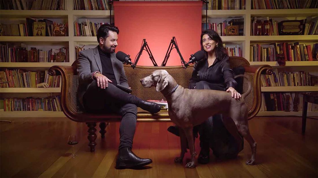 Dois apresentadores numa biblioteca com um cão, videocast